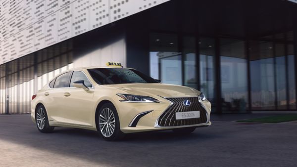 Ein Lexus ES 300h Vollhybrid-Taxi parkt vor einem Gebäude mit Glasfassade