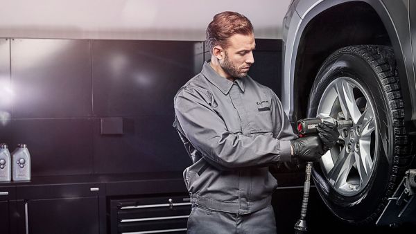 Ein Mechaniker schraubt einen Reifen an einem Lexus fest