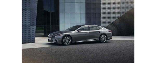 Ein grauer Lexus LS seitlich geparkt in einer modernen, städtischen Umgebung 