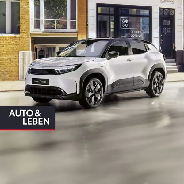 Ein schnittiger weißer Elektro-SUV steht auf einer modernen städtischen Straße, an der eine stilvolle Frau vorbeigeht